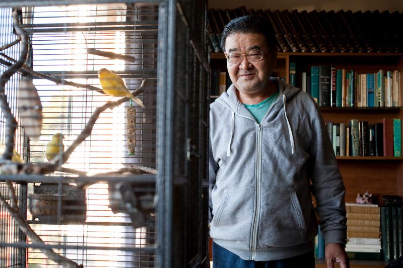 A man looking at birds in a cage