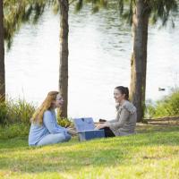 Two women talking by a lake